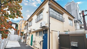 A residential building with multiple balconies, a blue door, and a gated entrance. - Experience life in a private old private house in the heart of Tokyo｜3 bedrooms, 5 beds｜Excellent access to Akasaka, Roppongi, Ginza, Aoyama, Harajuku, Imperial Palace｜with private workspace (港区)