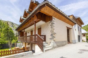 A two-story chalet with a wooden facade, stone accents, and a balcony with a wooden railing. - 50m from ski slopes, 1st floor, tv, ski locker, 32m², Valloire (Valloire)