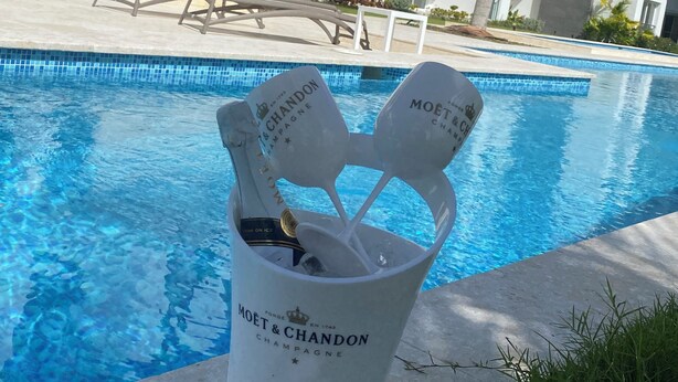 Zona junto a la piscina con un balde que contiene botellas de champán Moët & Chandon y copas.