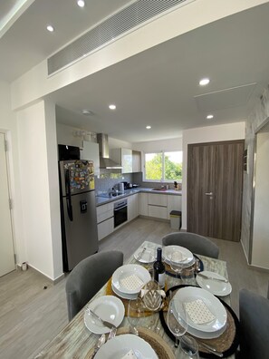 Una cucina moderna con forno a microonde integrato, forno e lavello. C'è un'area pranzo con un tavolo apparecchiato per quattro, inclusi piatti, bicchieri e posate.