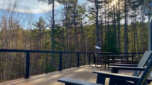 A wooden deck with benches and a railing overlooking a forest. - Spacious Yard & Deck - Hot Tub - 120” Projector - 12mins-Waterville Valley (Thornton)