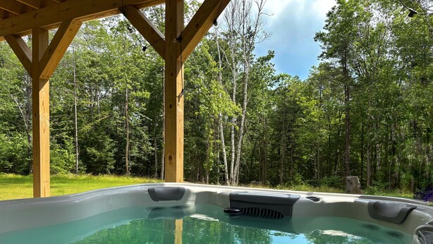 A hot tub under a wooden gazebo surrounded by a forest. - Spacious Yard & Deck - Hot Tub - 120” Projector - 12mins-Waterville Valley (Thornton)