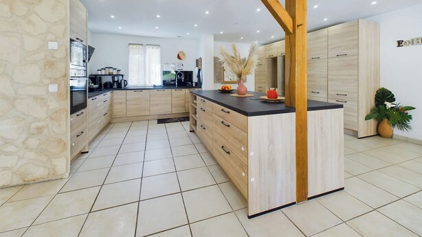 Eine moderne Küche mit einer zentralen Kochinsel, Holzschränken und einer Wand als Akzent mit Stein.