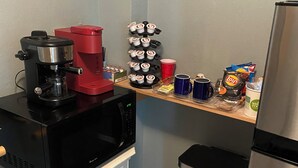 A compact kitchenette with a coffee maker, microwave, and a small trash bin. - Charming studio in beautiful Palm Harbor with A/C, Swimming Pool and Patio (Palm Harbor)