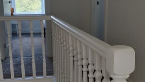 Escadaria com corrimãos brancos que leva a um patamar com vista para uma área residencial.