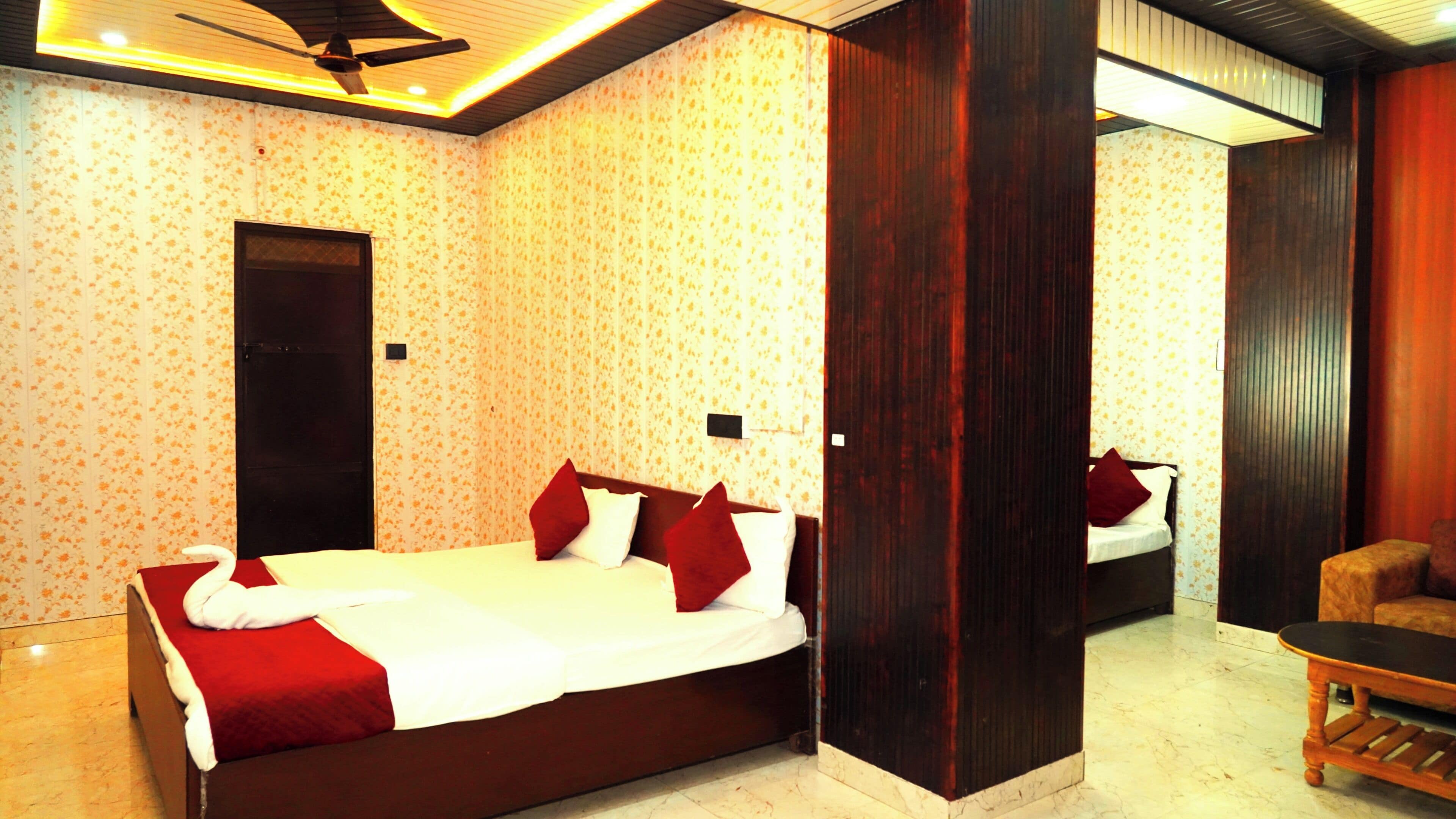 A hotel room with a large bed, a wooden wardrobe, and a small seating area.