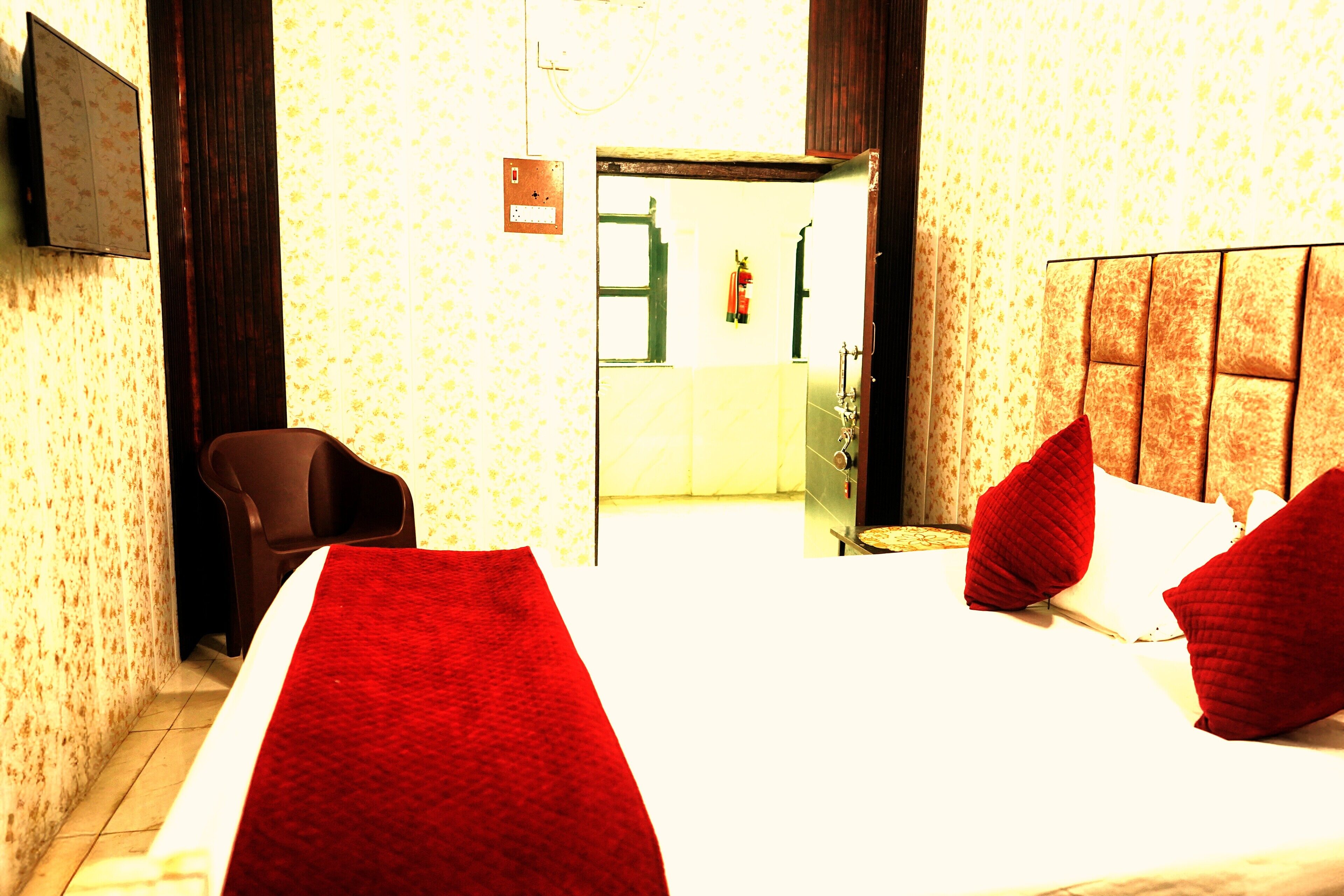 Ein Hotelzimmer mit Bett, Sessel und Fernseher an der Wand.