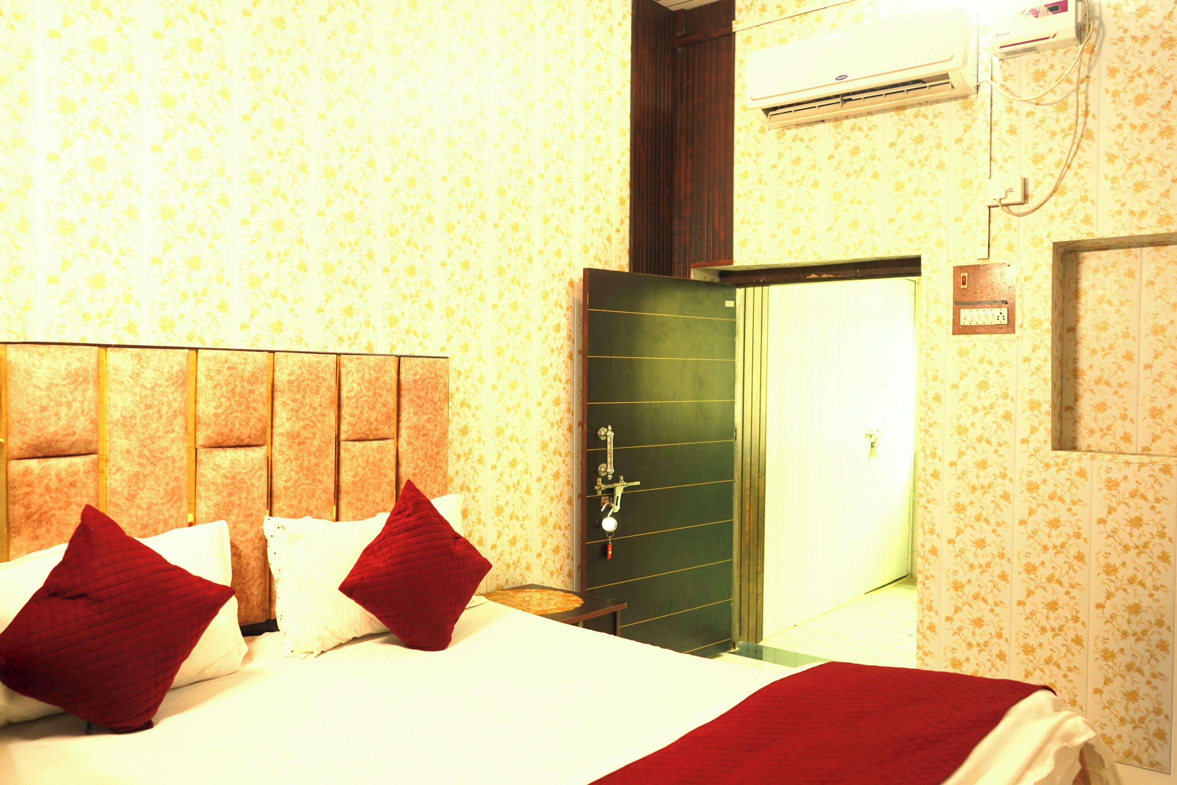 A hotel room with a bed, pillows, a nightstand, and a door.