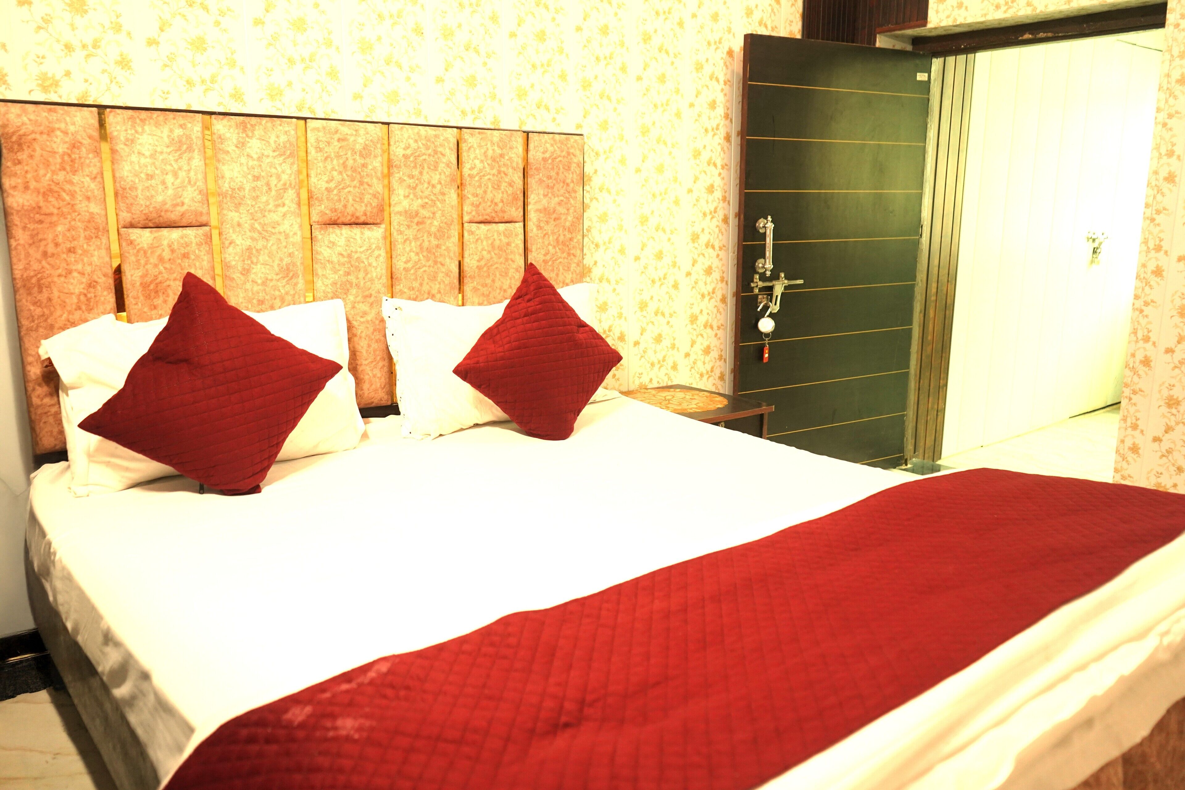 Une chambre d’hôtel avec un grand lit, deux oreillers rouges, un couvre-lit blanc et une couverture rouge.