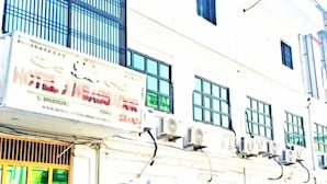 A building with a sign for a hotel named "HOTEL GRAND." There are multiple windows and air conditioning units on the exterior. - Hotel Ambassador Grand (Varanasi)