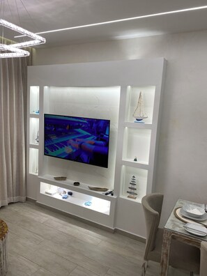 Un salon moderne avec un grand téléviseur à écran plat fixé sur un meuble de télévision blanc.