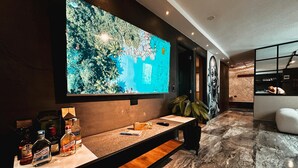 A modern bar area with a large flat-screen TV mounted on the wall, a marble countertop, and a seating bench. - Vacation Home (For Friends and Family) (Medellín)