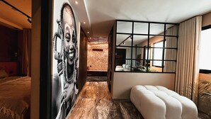 A modern hotel room with a large mirror, a plush ottoman, and a mural on the wall. - Vacation Home (For Friends and Family) (Medellín)