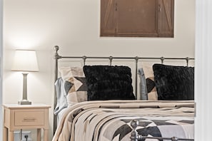 Une chambre à coucher avec un lit en métal, une table de chevet avec une lampe et une armoire en bois au-dessus du lit.