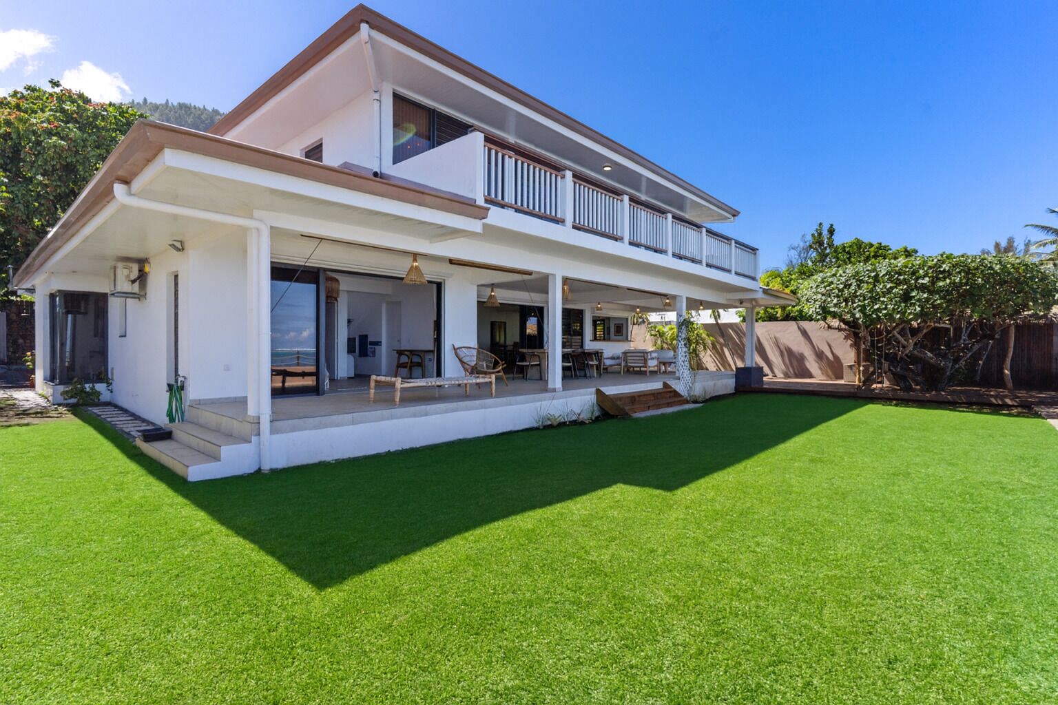 A two-story house with a covered patio, a swimming pool, and a well-maintained lawn.