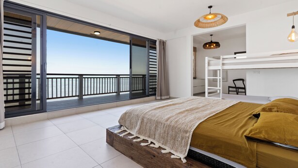 A bedroom with a large window, a bunk bed, and a view of the sky. - Hinarani Villa (Paea)