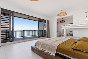Un dormitorio con un ventanal grande, una cama litera y vista al cielo.
