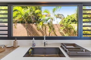 Una cocina con un amplio ventanal que da a un jardín tropical.