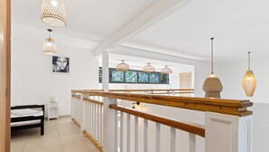 A modern interior with a wooden staircase, white walls, and pendant lighting. - Hinarani Villa (Paea)