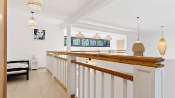 A modern interior with a wooden staircase, white walls, and pendant lighting.
