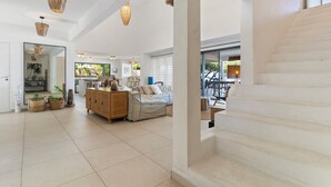 A spacious living area with a staircase, a wooden cabinet, and a sofa. - Hinarani Villa (Paea)