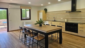 A modern kitchen with a wooden dining table, black chairs, and a black stove. - Rural lodging with swimming pool in front of the Cueva del Gato, 9 km from Ronda. (Benaoján(Málaga))
