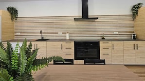 A modern kitchen with wooden cabinets, a black stove, and a striped backsplash. - Rural lodging with swimming pool in front of the Cueva del Gato, 9 km from Ronda. (Benaoján(Málaga))
