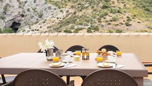 A dining table set with breakfast items, including toast, eggs, and orange juice, overlooking a mountainous landscape. - Rural lodging with swimming pool in front of the Cueva del Gato, 9 km from Ronda. (Benaoján(Málaga))