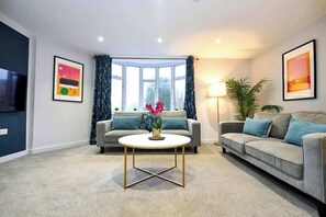 A living room with two sofas, a coffee table, a TV, and framed artwork on the walls.