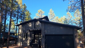 A modern two-story house with a garage, surrounded by tall pine trees. - Beautiful 3-bedroom cabin in welcoming Pinetop Country Club (Pinetop Country Club)