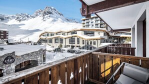 Un hôtel situé devant une montagne enneigée, doté d’un balcon en bois et d’une arche en pierre.