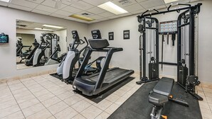 Ein Fitnessstudio mit Laufbändern, Kraftgeräten und einer Spiegelwand.