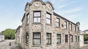 Un edificio de piedra con varias ventanas y una entrada en esquina.