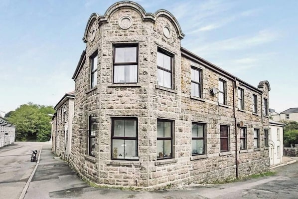 A stone building with multiple windows and a corner entrance.