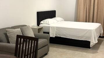 Una habitación de hotel con una cama, un sofá, una mesa y una silla.