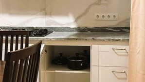 Cocina compacta con armarios blancos, encimera de mármol y horno integrado.