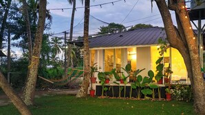 A house with a porch, surrounded by trees and potted plants.