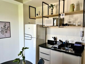 Comfort studio | Privékeuken | Een koelkast, een magnetron, een kookplaat, kookgerei, borden en bestek