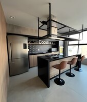 Uma cozinha moderna com frigorífico embutido, ilha para cozinhar e banquetas.
