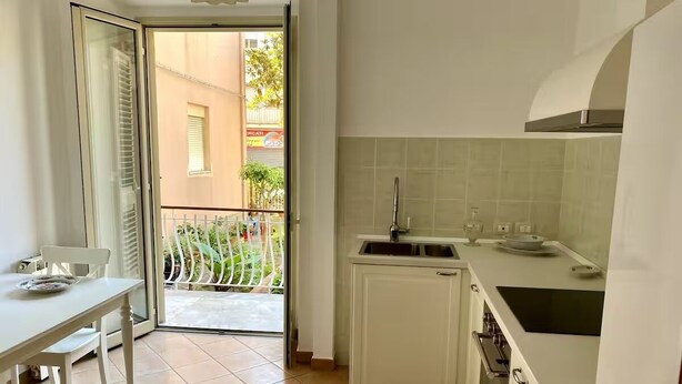 A compact kitchen with a dining area, a sliding glass door leading to a balcony, and a small oven.