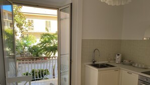 A compact kitchen with a sink, stove, and a dining area with a table and chairs.