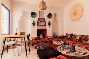 A cozy living room with a sofa set, a dining table, and a fireplace. - Ifni Sunset (Sidi Ifni)