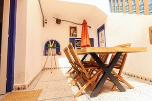 A room with a wooden table, chairs, a small easel, and a framed picture on the wall. - Ifni Sunset (Sidi Ifni)