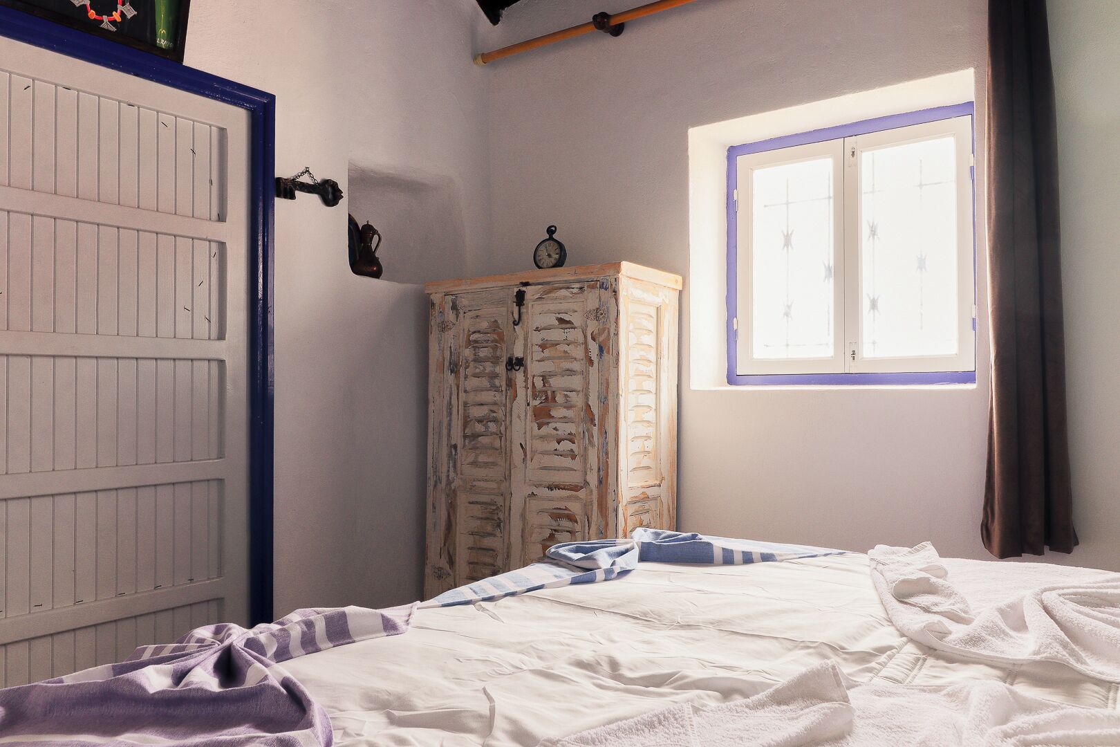 A bedroom with a bed, a wardrobe, a window, and a door.