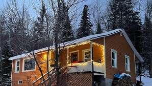 A wooden house with a porch, surrounded by snow and trees. - Cozy 3 bd, 8 min North Side Tremblant ski lifts (Lac-Supérieur)