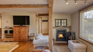 A cozy living room with a fireplace, wooden furniture, and a television. - Cozy 3 bd, 8 min North Side Tremblant ski lifts (Lac-Supérieur)