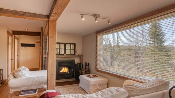 A cozy room with a fireplace, a sofa, and a window with blinds. - Cozy 3 bd, 8 min North Side Tremblant ski lifts (Lac-Supérieur)