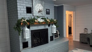 A modern living room with a grey brick fireplace, a decorative mantel, and a geometric rug. - FARMHOUSE 89 (Bryant)