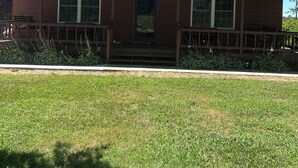 A two-story house with a metal roof, a front porch, and a small front yard. - FARMHOUSE 89 (Bryant)