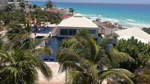 A resort with a pool area, palm trees, and a view of the ocean. - Beach Front Flat!! (Cancún)
